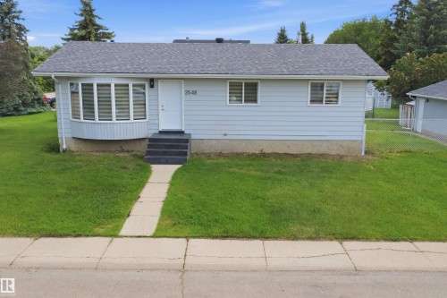 Gray siding home featuring a shingled roof, a bay window with horizontal blinds, and a white front entry door - 3548 20 Ave, Edmonton, AB 