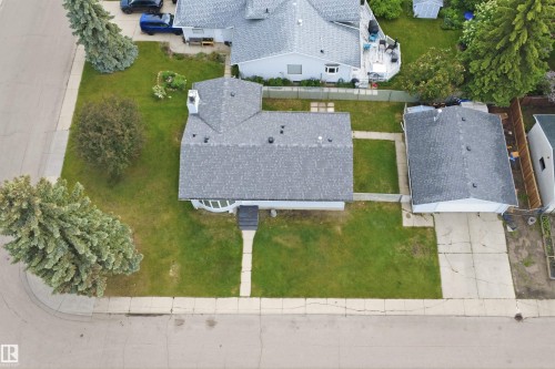 Corner lot property featuring a detached garage, mature landscaping, and a paved driveway - 3548 20 Ave, Edmonton, AB 