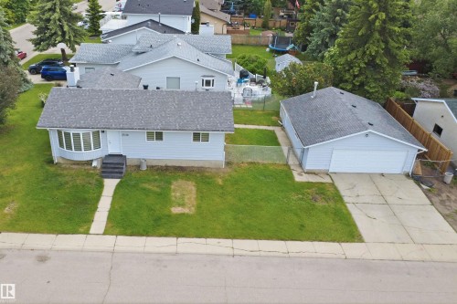 Light blue siding residence featuring a bay window, dark grey shingle roof, concrete front steps, and an attached two-car garage with a concrete driveway - 3548 20 Ave, Edmonton, AB 
