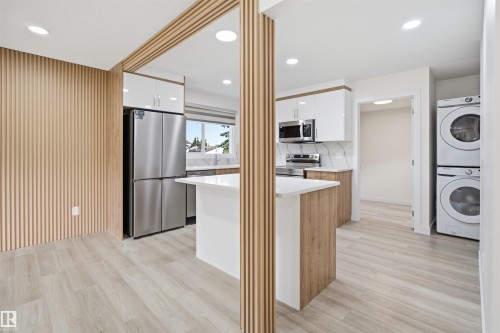 Contemporary kitchen featuring a white island, stainless steel appliances, and two-tone cabinetry - 3548 20 Ave, Edmonton, AB 