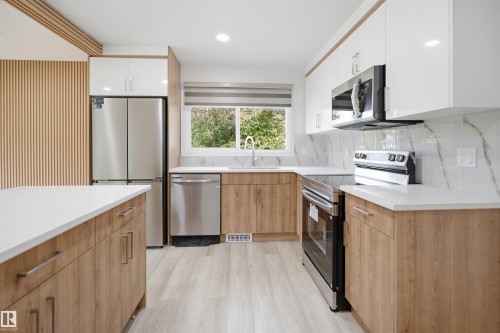 Modern kitchen with wood-finish base cabinetry, white upper cabinets, and white countertops - 3548 20 Ave, Edmonton, AB 