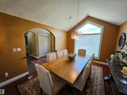 Dining space featuring a vaulted ceiling and an arched window - 