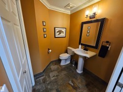 Powder room featuring earthy wall tones and slate-style floor tiling - 