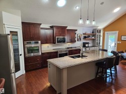 Gourmet kitchen featuring rich wood cabinetry, stainless steel appliances, and wood-finish flooring - 