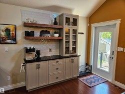 Custom built-in cabinetry with dark countertops, two floating wood shelves, and a tiled backsplash - 
