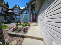 Front exterior featuring light gray siding, a prominent gabled entry, and a contrasting red entry door - 