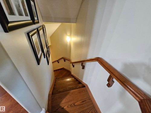 Staircase featuring wood-finish treads and risers, complemented by a solid wood handrail with decorative supports - 2322 Rutherford Way, Edmonton, AB 