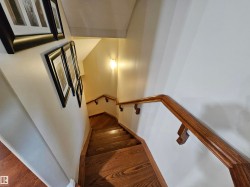 Staircase featuring wood-finish treads and risers, complemented by a solid wood handrail with decorative supports - 