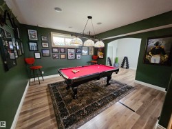 Recreation room featuring wood-finish flooring, recessed lighting, and an arched entryway - 