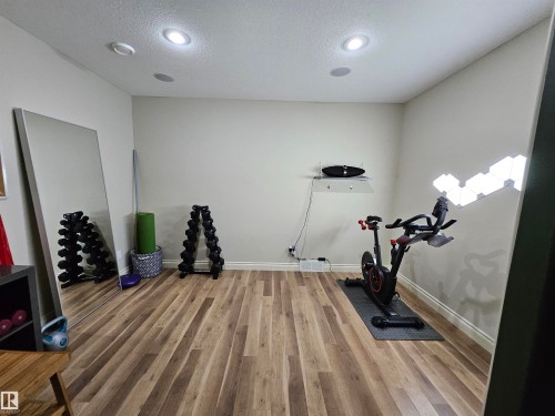 Recessed ceiling lighting illuminates a room with wood-finish flooring and light-toned walls - 2322 Rutherford Way, Edmonton, AB 