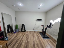 Recessed ceiling lighting illuminates a room with wood-finish flooring and light-toned walls - 