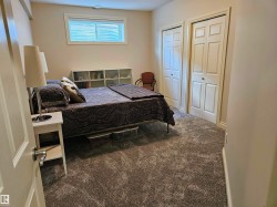 Bedroom featuring plush grey carpeting, two paneled closet doors, and a window with a white frame - 