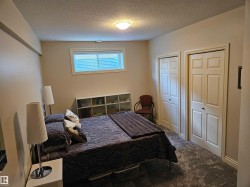 Spacious room featuring neutral wall paint, a low-profile window with blinds, and durable carpet flooring - 