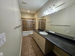 Bathroom featuring a double vanity with integrated sinks, a full-width mirror, and a shower-over-tub with sliding glass enclosure - 