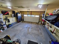 Spacious garage featuring a light-colored sectional overhead door with windows, a concrete floor, and integrated overhead lighting - 