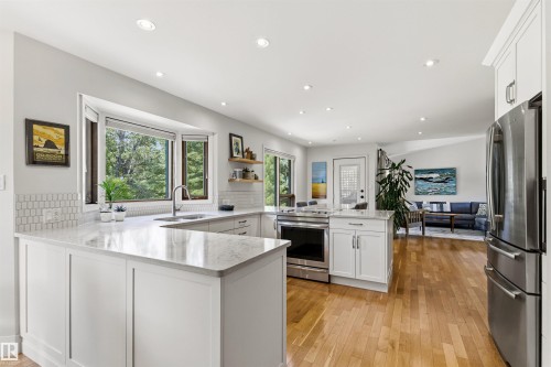 Bright kitchen featuring white cabinetry, light-toned countertops, and a bay window overlooking exterior greenery - 624 Butchart Wynd, Edmonton, AB 