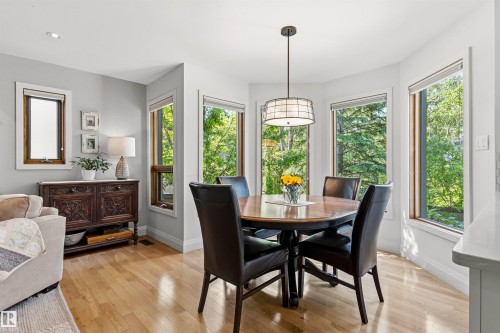 Dining area featuring abundant natural light from multiple windows, a decorative pendant light fixture, and wood-finish flooring - 624 Butchart Wynd, Edmonton, AB 