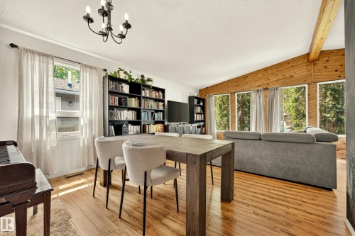 Open-concept living space featuring wood-finish flooring, a vaulted ceiling with exposed wood beams, and a wall of windows - 24 Addison Crescent, St. Albert, AB 