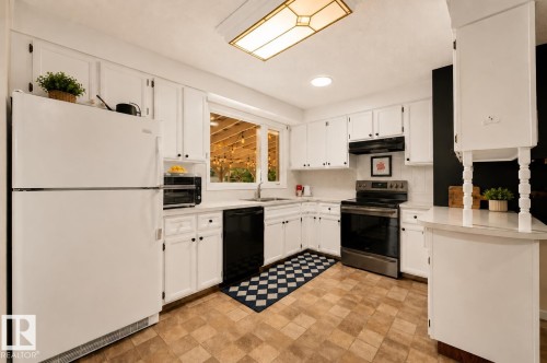 Kitchen featuring white cabinetry, white countertops, stainless steel appliances, and wood-finish flooring - 24 Addison Crescent, St. Albert, AB 