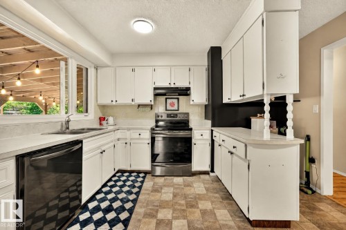 U-shaped kitchen featuring white cabinetry, light countertops, and a black appliance suite - 24 Addison Crescent, St. Albert, AB 