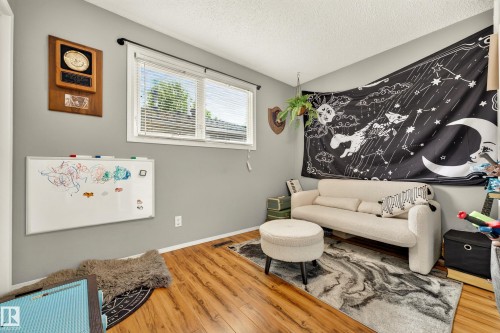 Spacious room featuring wood-finish flooring and a large window with white blinds - 24 Addison Crescent, St. Albert, AB 