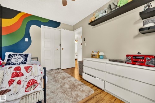 Bedroom with wood-finish flooring, a neutral wall color, and a statement accent wall - 24 Addison Crescent, St. Albert, AB 