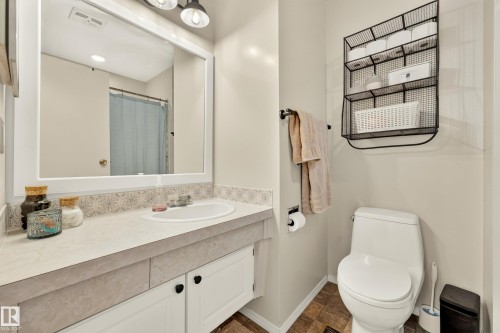 Bathroom vanity featuring an integrated sink, white cabinetry, and a framed mirror - 24 Addison Crescent, St. Albert, AB 