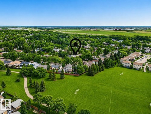 Expansive green space featuring a large field with soccer goals, bordered by mature trees and a paved walking path - 24 Addison Crescent, St. Albert, AB 