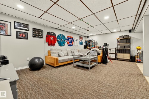 Spacious room featuring neutral-toned carpet flooring, light gray walls, and a white grid ceiling with recessed lighting - 24 Addison Crescent, St. Albert, AB 