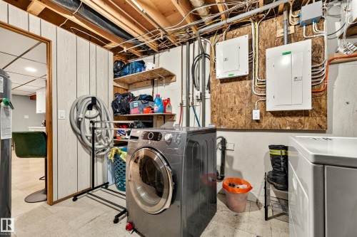 Dedicated utility area featuring exposed ceiling joists, two electrical panels, paneling on walls, and open shelving storage - 24 Addison Crescent, St. Albert, AB 