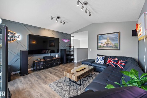 Living area featuring a geometric accent wall with mounted television, track lighting, and wood-finish flooring - 363 Cy Becker Boulevard, Edmonton, AB - Indoor Photo Showing Living Room