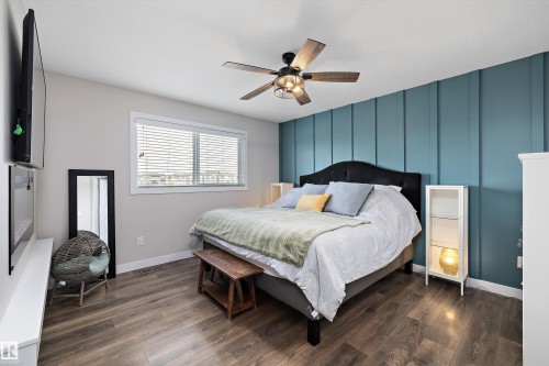 Bedroom featuring wood-finish flooring, a decorative accent wall, a ceiling fan with integrated lighting, and a double window with horizontal blinds - 363 Cy Becker Boulevard, Edmonton, AB - Indoor Photo Showing Bedroom