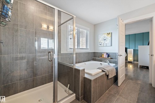 Full bathroom featuring a glass-enclosed shower with tile surround, a built-in bathtub with tiled deck, a window with blinds, and tile flooring - 363 Cy Becker Boulevard, Edmonton, AB - Indoor Photo Showing Bathroom