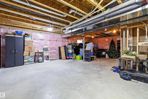 Unfinished basement featuring exposed wood joists, concrete flooring, pink insulation, and visible utility conduits - 363 Cy Becker Boulevard, Edmonton, AB - Indoor Photo Showing Basement