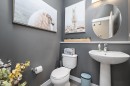 Powder room featuring a pedestal sink, round mirror, and a wall-mounted light fixture - 363 Cy Becker Boulevard, Edmonton, AB  - Indoor Photo Showing Bathroom 