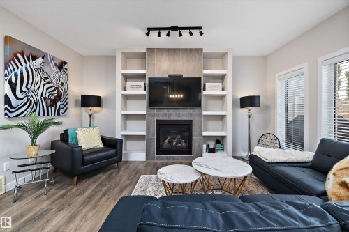 Living area featuring a fireplace with a tiled surround, integrated shelving, and track lighting - 363 Cy Becker Boulevard, Edmonton, AB - Indoor Photo Showing Living Room With Fireplace