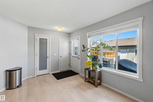 Light wood-finish flooring complements the neutral wall color in this space, featuring a large window with white trim - 940 East Gate, Edmonton, AB 
