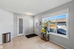 Light wood-finish flooring complements the neutral wall color in this space, featuring a large window with white trim - 