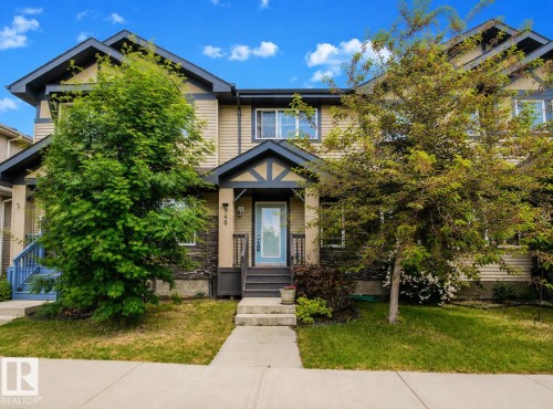 Multi-level townhouse exterior featuring beige siding, stone accents, and a contrasting dark trim - 940 East Gate, Edmonton, AB 