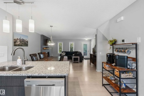 Kitchen island with a double basin stainless steel sink, granite-finish countertop, and stainless steel dishwasher - 940 East Gate, Edmonton, AB 