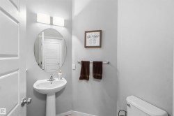 Pedestal sink with an oval mirror, modern wall-mounted light fixture, and light-toned walls - 