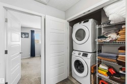 Dedicated laundry closet featuring a stacked washer and dryer, adjacent to wire shelving storage - 