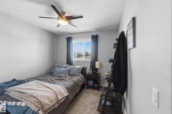 Bedroom featuring a ceiling fan with integrated lighting, a window with horizontal blinds, and neutral-toned carpeting - 