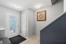 Bright entry featuring a full-light panel door, wood-finish flooring, and a contemporary flush-mount ceiling light - 940 East Gate, Edmonton, AB 