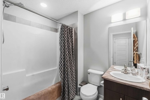 Bathroom featuring a single vanity with a stone-finish countertop, undermount sink, and a framed mirror - 940 East Gate, Edmonton, AB 