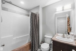 Bathroom featuring a single vanity with a stone-finish countertop, undermount sink, and a framed mirror - 