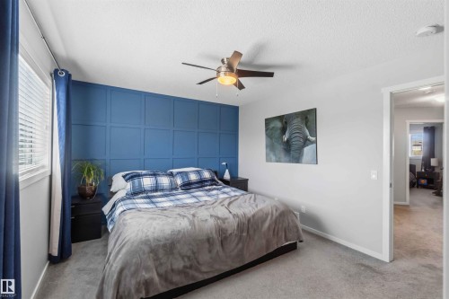 Bedroom featuring a full-wall accent paneling, overhead ceiling fan with integrated lighting, and carpet flooring - 940 East Gate, Edmonton, AB 