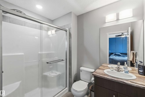 Bathroom featuring a glass-enclosed shower with a built-in seat, single vanity with an oval basin, and a wall-mounted light fixture - 940 East Gate, Edmonton, AB 