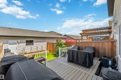 Spacious composite deck with white railing, privacy fencing, a manicured lawn, and an overhead pergola structure - 