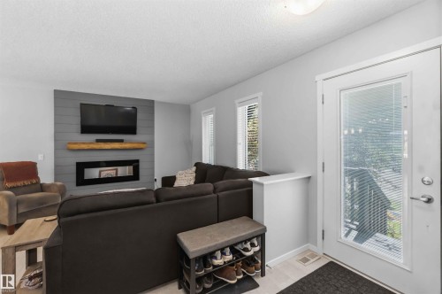 Living area featuring a shiplap accent wall with an inset electric fireplace and wood-finish mantel - 940 East Gate, Edmonton, AB 